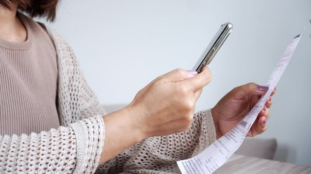 woman using smartphone to scan a qr code and make a contactless payment for electricity bills, taxes, or other household expenses from home, quick, safe, and convenient way to manage monthly payment