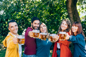 Friends toasting with beer mugs in garden party celebration
