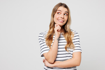 Obraz premium Young happy smiling woman she wear striped t-shirt casual clothes put hand prop up on chin, lost in thought and conjectures isolated on plain solid white background studio portrait. Lifestyle concept.