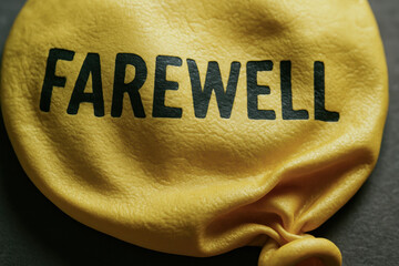 Yellow deflated balloon with farewell text symbolizes concept of termination and end of joyful event or celebration