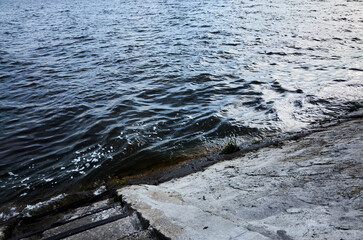 Minimalist image of a concrete shore where gentle river waves meet the structure, creating a calm and textured natural scene. Perfect for background use, environmental themes