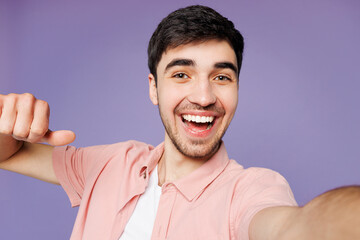 Close up young man he wears pink shirt t-shirt casual clothes doing selfie shot pov on mobile cell phone point on himself isolated on plain pastel purple background studio portrait. Lifestyle concept.