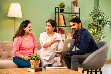 Indian mother and daughter consult male advisor for insurance or loan in cozy home interior