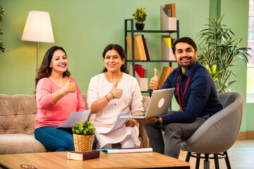 Indian mother and daughter consult male advisor for insurance or loan in cozy home interior