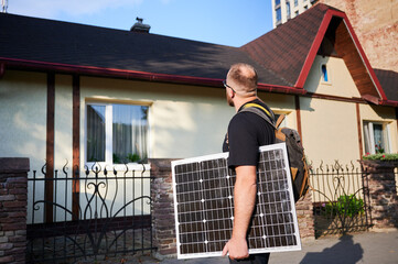 Man holding photovoltaic solar panel in front of historical building. Concept of integration of...