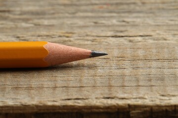 One sharp graphite pencil on wooden table, closeup. Space for text