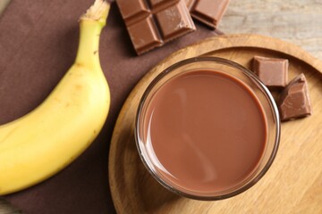 Tasty chocolate milk, pieces and banana on table, flat lay