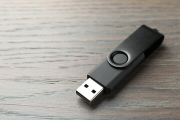 One flash drive on wooden background, closeup. Space for text