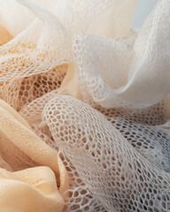 Abstract composition of intertwined white and peach knitted mesh creating flowing shapes and fine organic patterns under gentle light.