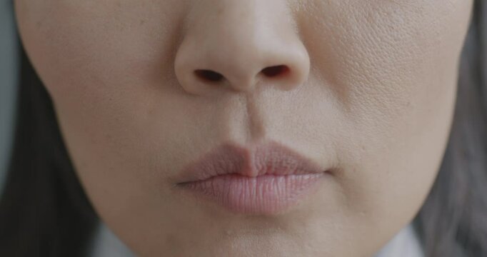 Close-up slow motion portrait of young woman's mouth expressing anxiety while lady feeling worried and nervous. People and negative emotion concept.