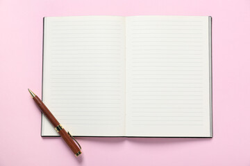 Open blank notebook and pen on pink background, top view