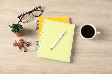 Flat lay composition with office supplies, cup of coffee and houseplant on wooden table