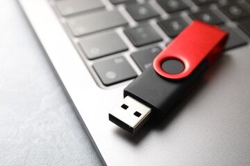 Modern flash drive and laptop on light grey table, closeup