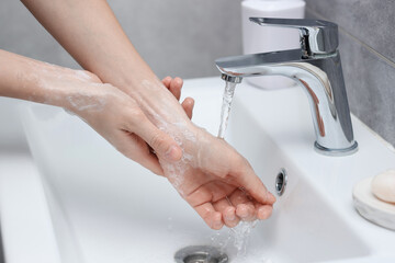 Woman washing hands at sink in bathroom, closeup