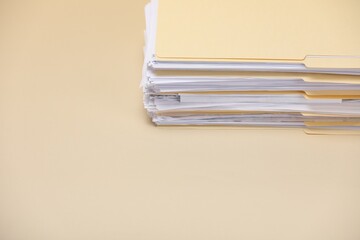 File folders with papers on pale yellow background, closeup. Space for text
