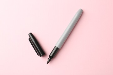 One black marker on light pink background, top view