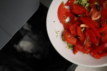 Cockroaches and vegetables in bowl near trash bin, top view