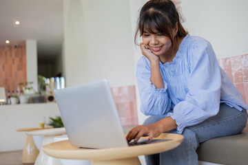 Digital nomad working on business project in coffee shop smiles while using laptop in cozy and relaxed atmosphere