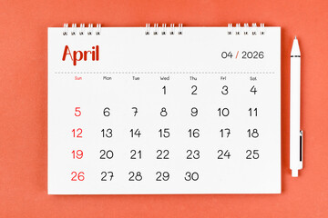 April 2026 Monthly desk calendar for 2026 year and pen on red background.