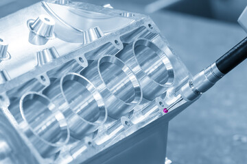 The multi axis CMM machine measuring the aluminum cylinder block parts in the light blue scene.