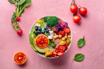 Buddha Bowl. Rainbow salad. Vegan poke bowl with avocado. Healthy food. Overhead flat lay shot with ingredients on a pink table