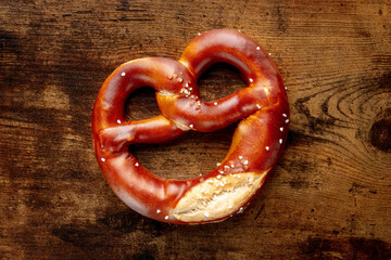 Pretzel or Bretzel, traditional German beer snack, a wheat bread with salt, overhead flat lay shot on a wooden background