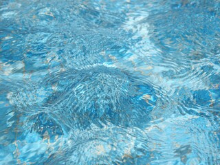 Fondo abstracto,agua en una pequeña piscina con olas y reflejos de luz solar