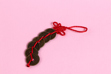  6 Chinese coins  with a red string on a pink background