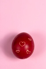 Red painted Easter egg with white hearts on a pink background