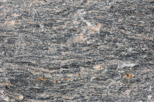 Natural beauty and intricate patterns of textured rough granite stone with gray and cler pink colors.