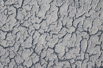 Cracked old white paint on bitumen texture resembling a desert landscape illuminated by soft afternoon light