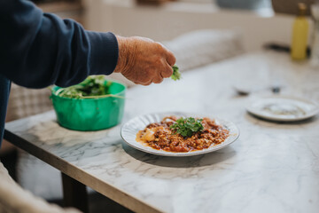 Preparation of a homemade meal featuring a person adding fresh herbs to a cooked dish on a white plate, representing cooking creativity and culinary presentation.