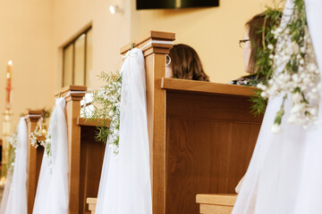 Flowers and Green Branches Decorating Church Pews for First Holy Communion