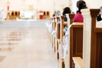 Flowers and Green Branches Decorating Church Pews for First Holy Communion