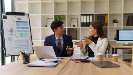 Young male and female colleagues collaborating on data and strategy during a meeting at a shared desk.