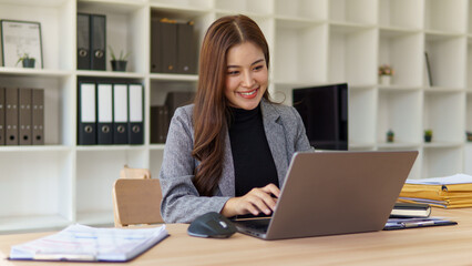 Confident businesswoman working on laptop at modern office desk.
