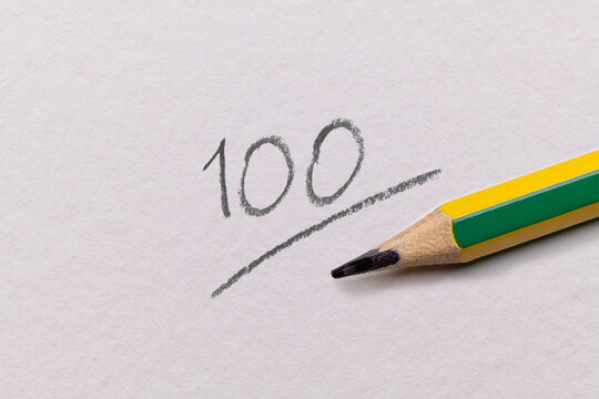red 100 full mark with pencil written on white paper. educational concept