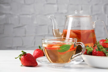 Aromatic fruit tea, strawberries and mint on white marble table, closeup