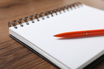 Pen and open notebook on wooden table, closeup