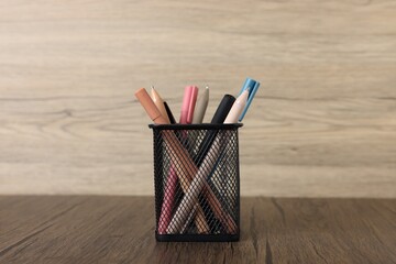 Ballpoint pens in holder on wooden table, closeup