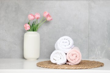 Clean towels and beautiful flowers on white table indoors