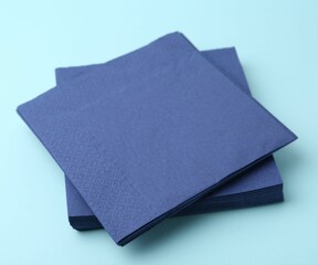 Stack of disposable paper handkerchiefs on light blue background, closeup