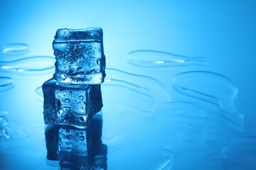 Cubes of clear ice on light blue background, space for text