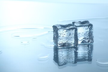 Cubes of clear ice on mirror surface, space for text
