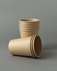 Disposable beige kraft paper cups on a gray closeup, mockup. No plastic and sustainable lifestyle