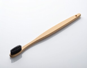 Close-up of a bamboo toothbrush with black bristles. The handle is light-colored and has a hole for hanging. It's placed on a white surface with soft shadows