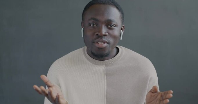 Portrait of African American man making online video call speaking looking at camera using earphones. Communication and virtual meeting concept.