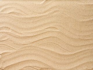 Beach sand background with natural wave pattern. Summer background of beach sand with small stones along the edges. Tourism, vacation and holidays concept. Top view.