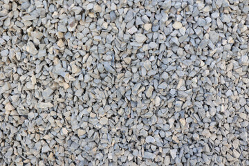 Close-up view of a uniform layer of gray crushed gravel stones, ideal for construction, road base, landscaping, or texture background. Natural rough texture with hard angular edges. High quality photo
