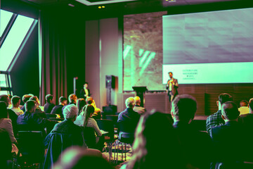 Speaker giving a talk in conference hall at business event. Rear view of unrecognizable people in...
